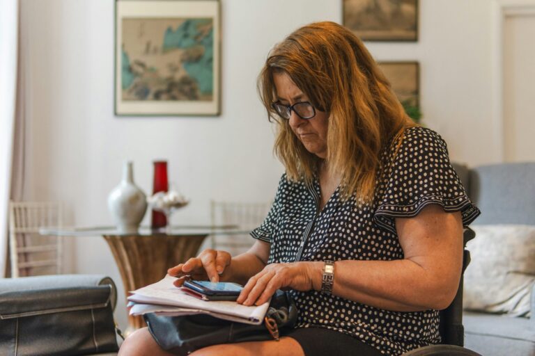vrouw die bezorgd de inkomsten en lasten doorrekent met alle papieren erbij